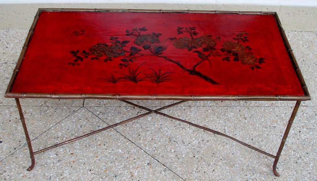Charming red japanned cocktail table mounted on faux bamboo metal frame with X-frame stretchers, probably from Maison Jansen.