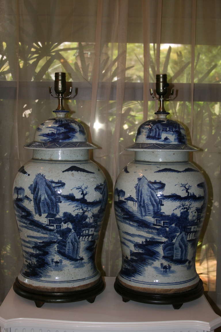 Handsome Pair of Large Blue and White Chinese  Lidded Temple Jars with Illustrative Landscape Designs Mounted on Lamps on Circular Black wooden Bases 
LGT69008