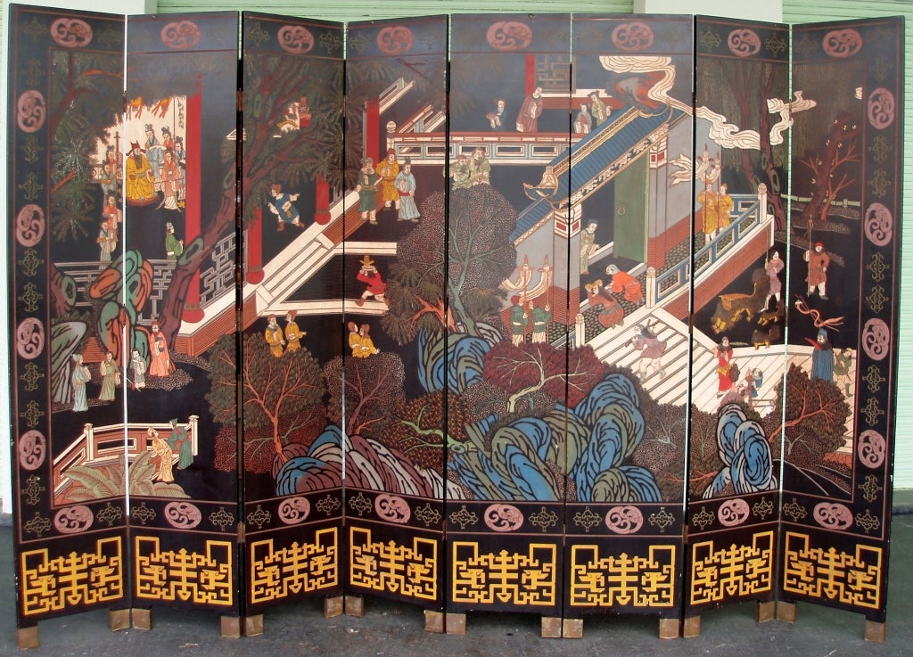 Very decorative and colorful eight-panel folding chinoiserie themed folding screen with engraved multi-figural designs, at the entrance of a royal palace, as seen from a side angle above with layers of lush multi-shaped trees and leaves at the