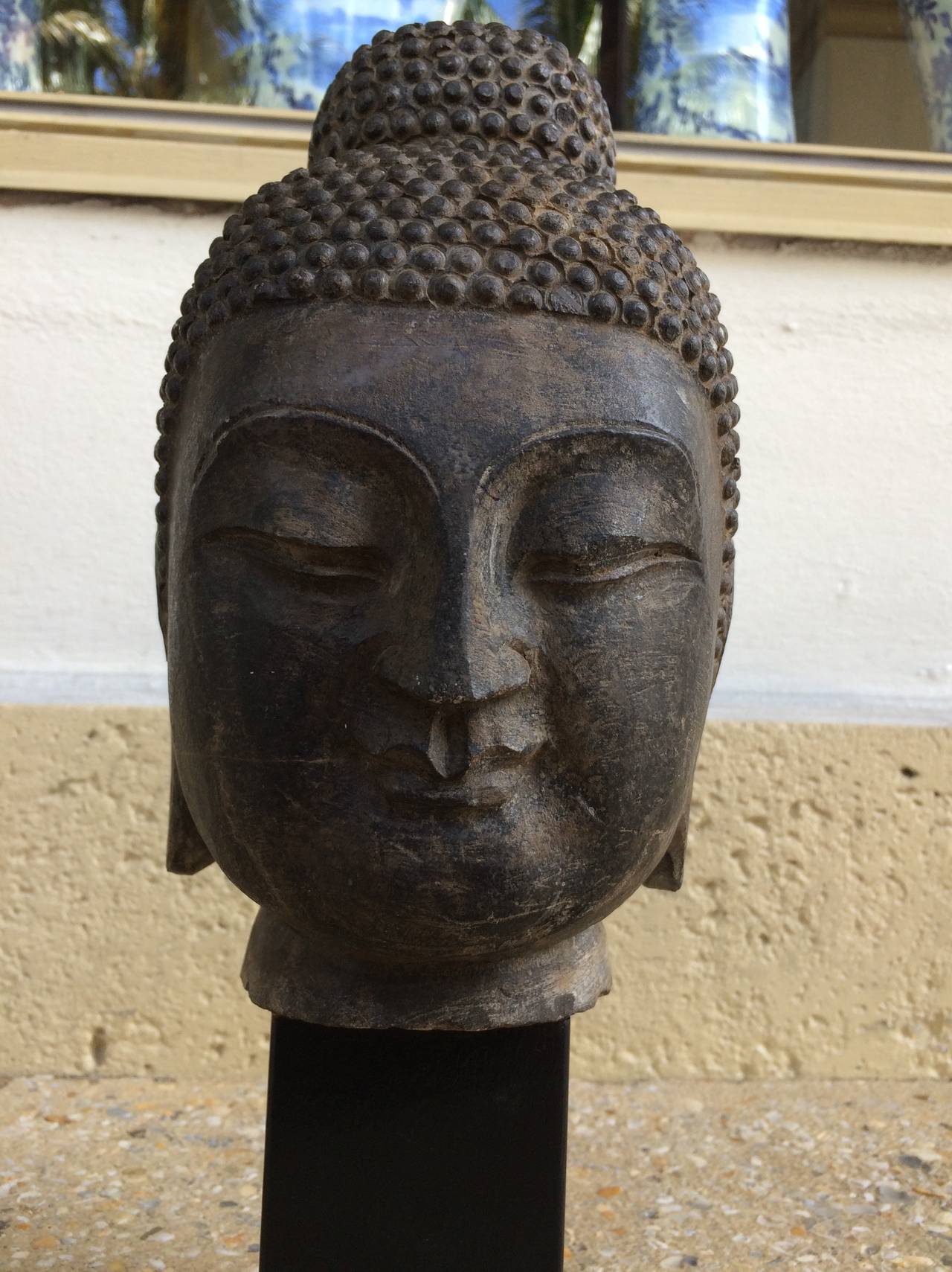 This is a magnificent carved and etched Chinese limestone head of Buddha, mounted on later ebony finished wood base.