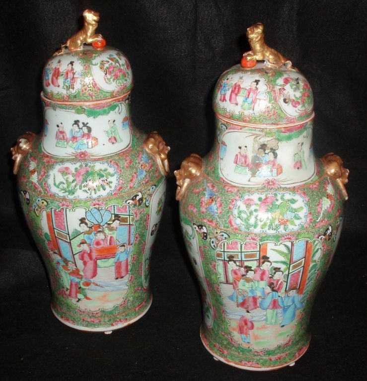 Pair of Chinese Export Rose Medallion Covered Jars with Large Mounted Gold Foo Dog Mask Handles, and Gold Foo Dog & Ball Finials on Lids, One Side of Each has Framed Panel showing Various Court Figures and Scholars within a Private Social Yard, and