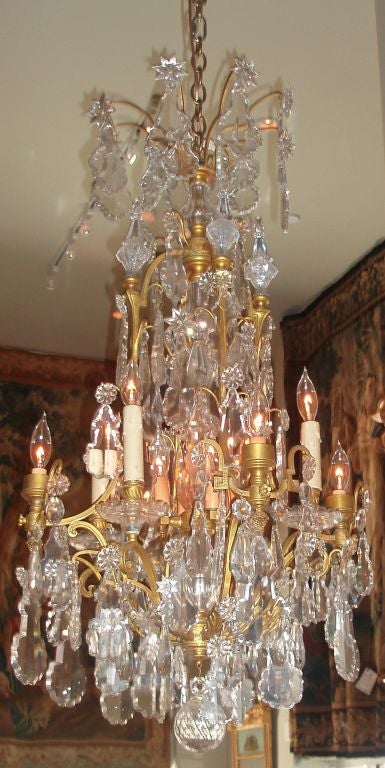 Stunning French bronze doré framed eight-arm chandelier with hanging cut crystals, detailed with flower and star-shaped accents throughout, and crystal casings on central stem with eight acanthus leaf under-mounts finishing with a multi-faceted