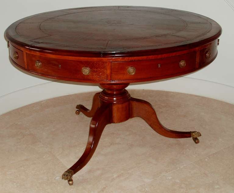 Fine mid to late Regency period revolving center table, polished mahogany form with similarly colored leather top embossed with gilt details above four dummy drawers and four functioning drawers, each with double ring handle pulls and mounted on a