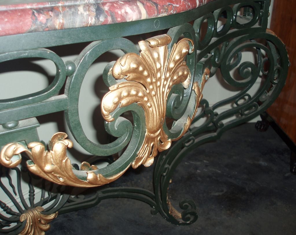 Charming painted and parcel-gilt Italian wall console, variegated dark red marble top with bow front, resting on decorative and curved forged iron base with gilt acanthus detailing on knees and scrolled feet.