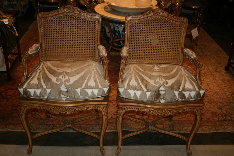 Louis XV style carved oak fauteuils with cane backs and custom upholstered with silk and cotton ikat-style box cut seat cushions in taupe and cream colors.
