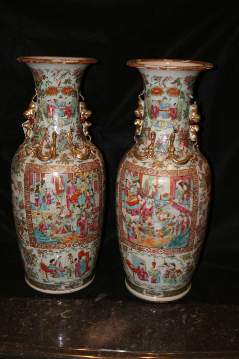 Stunning pair of famille rose, Chinese vases, trumpet style rims with gold finished foo lion handles, horizontally double mount facing lizards on front and back, floral and figural background designs through, framing multiple figural imperial court