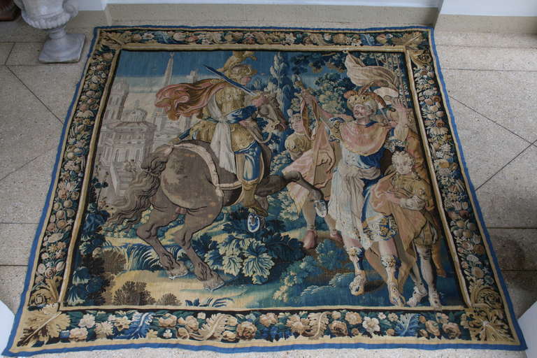 17th-18th century Flemish tapestry depicting an armored man on rearing horseback approaching a group of figures in a wooded landscape.