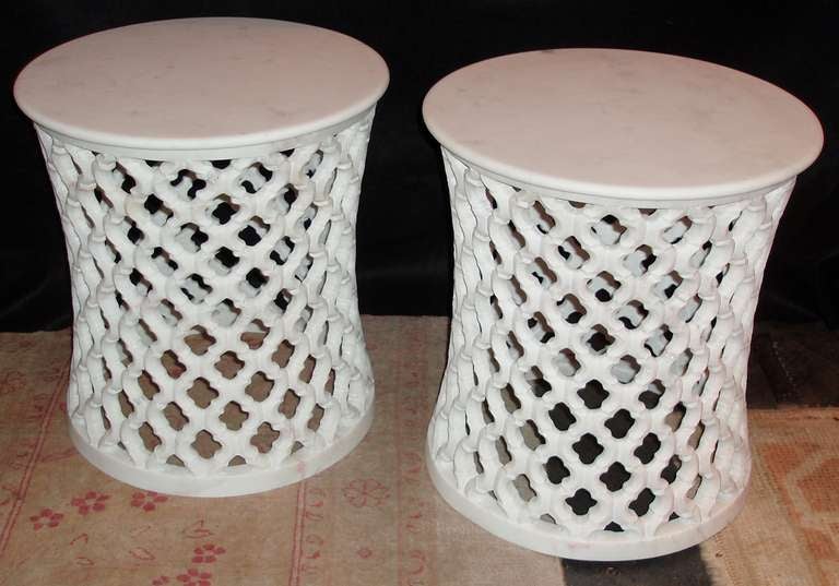 Moroccan style white marble drum tables, smooth circular form tops with natural honed finishes, center mounted on continual open pierced clover pattern designed bodies.
Finishing on smooth ring bases.