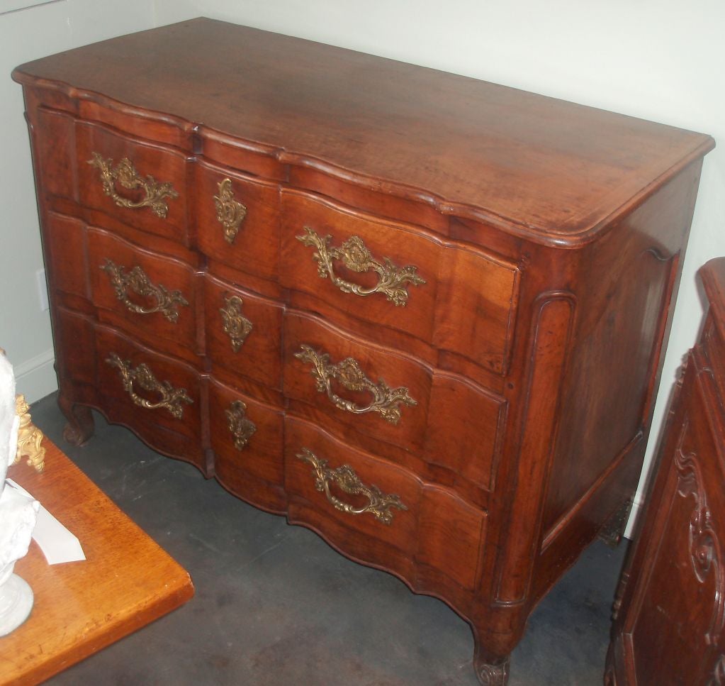 Very handsome carved and polished walnut Regence commode with scroll feet, consisting of three drawers; top one divided into three compartments and each with bronze dore' mounts. 