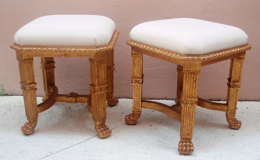 Very handsome giltwood finished carved wood tabouret with in-set muslin upholstered seat cushion, fluted legs ending with detailed lions feet extended by a bent framed design with a square floral mount. (Only a single piece)
