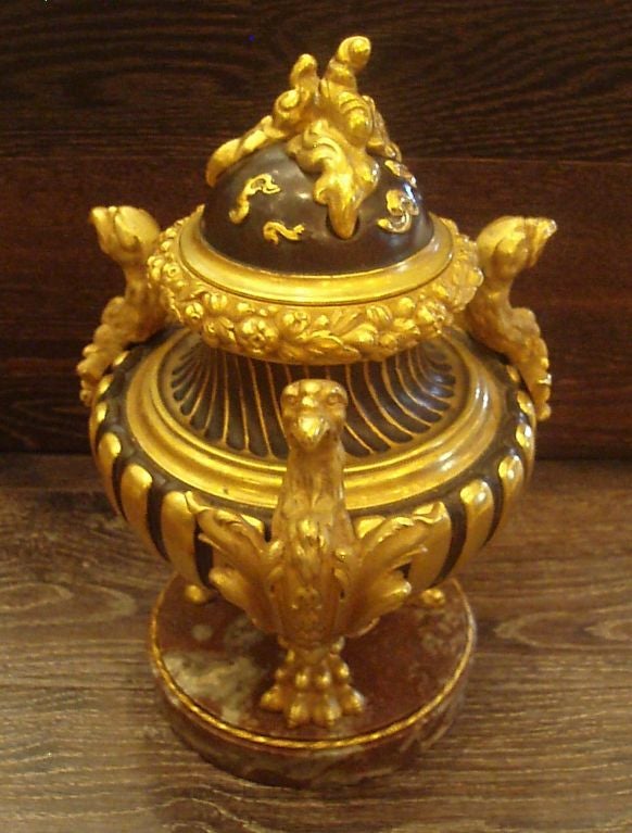 Decorative patinated and bronze doré lidded incense censor burner with tripodia phoenix bird supports set against a fluted bowl with dense floral wreath beneath a multi-cloud mounted dome lid raised on a variegated red marble base.