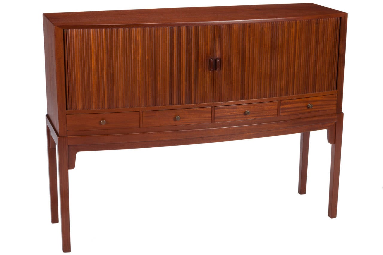 Rare and finely detailed teak server attributed to Ole Wanscher and manufactured by Rud Rasmussens. Cabinet with two tambour doors and interior slide-out shelf above four drawers. Rosewood pulls to tambour doors and brass pulls to four drawers.