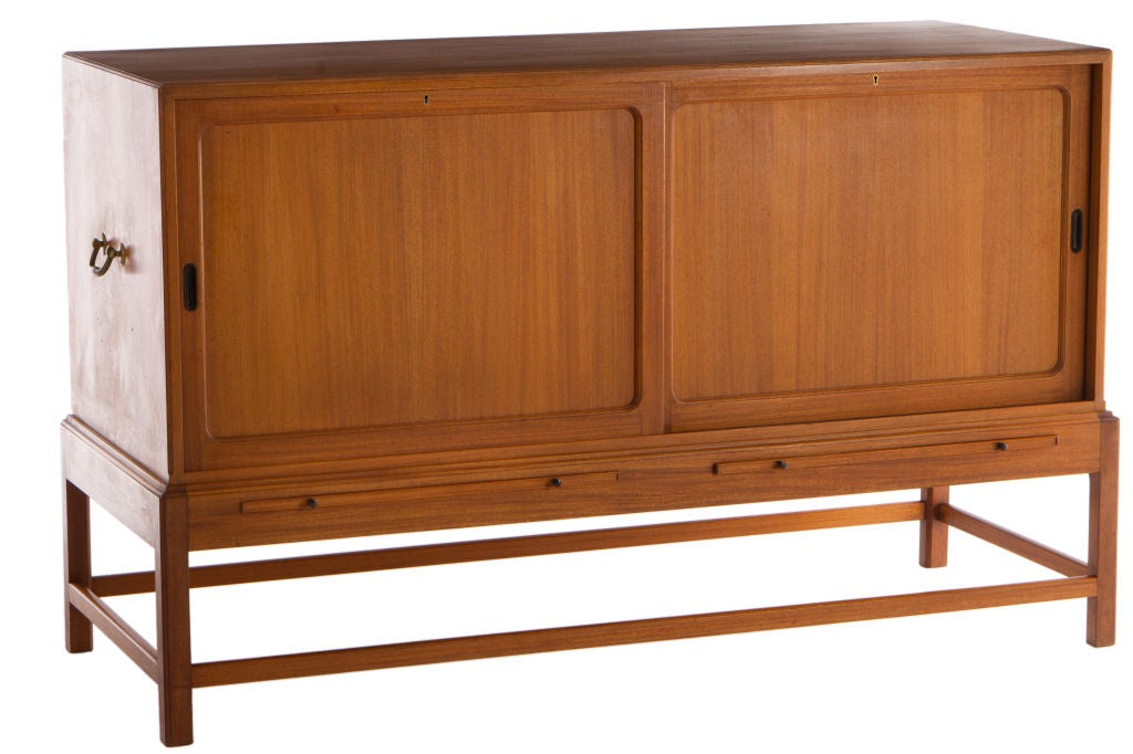Extremely well-constructed and elegant cabinet in Cuban ribbon mahogany by Kaare Klint and manufactured by Rud. Rasmussens, Denmark. Cabinet features two pull-out surfaces below two sliding doors concealing 15 adjustable drawers. Signed with applied