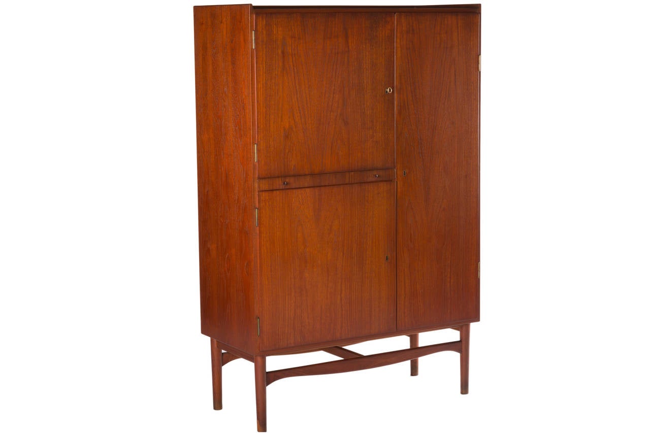 Rare minimal teak cabinet designed by Finn Juhl and manufactured by Bovirke.
Cabinet with three lockable doors (original key included) open to reveal an interior fitted with four adjustable shelves and eight adjustable drawers. There is also a