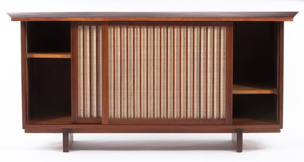 George Nakashima  designed American walnut cabinet with sliding doors with pandanus cloth,4 adjustable shelves,free-eddge top and double sided overhang.Cabinet comes with complete provenance.