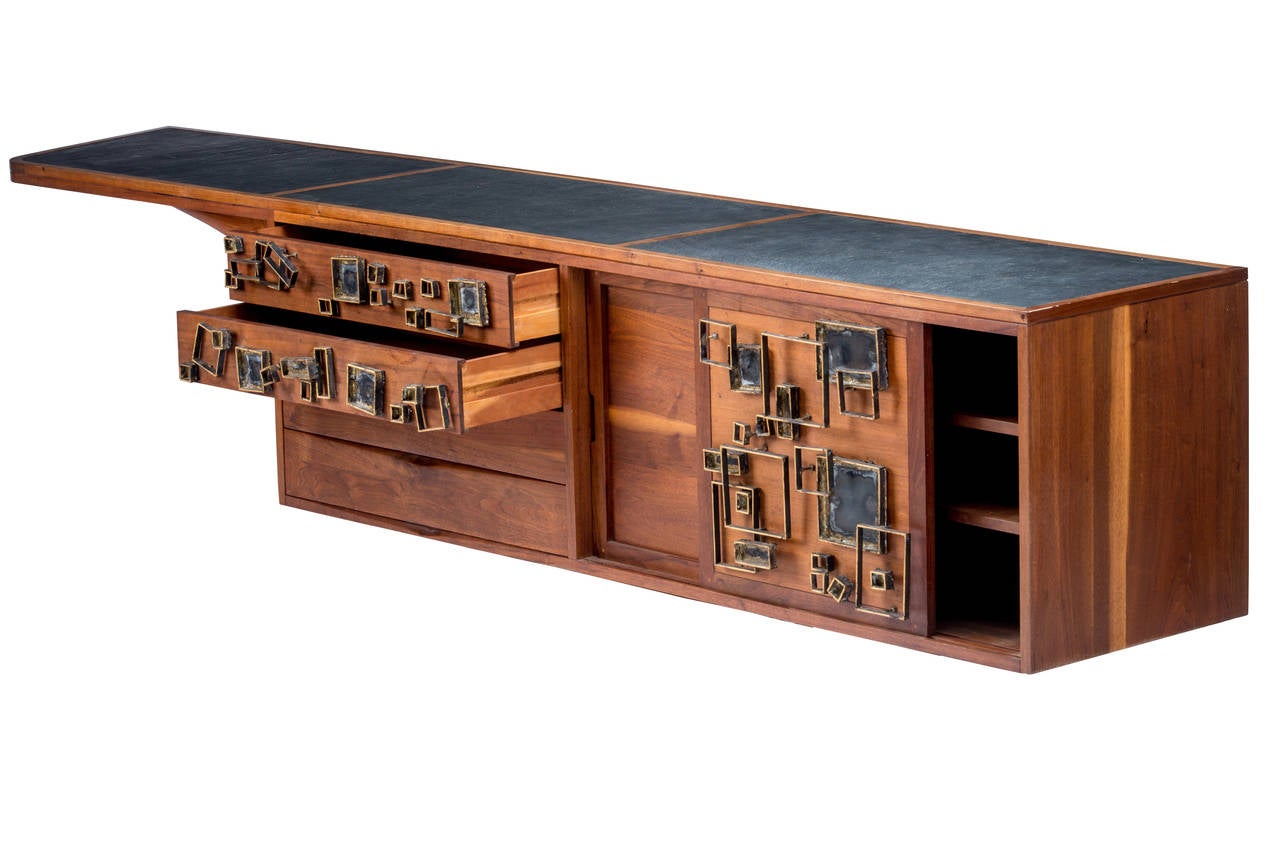 Rare and unique and large wall-hanging cabinet made in collaboration with Phil Powell and Paul Evans. The cabinet which was designed and built by Powell features four drawers, two sliding doors concealing storage and four adjustable shelves. The