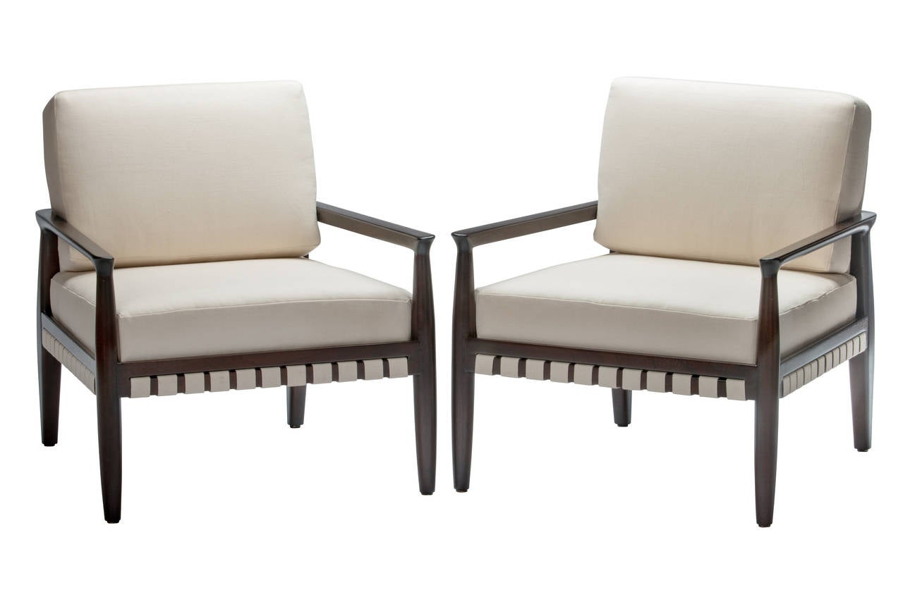 Elegant pair of Tommi Parzinger webbed and upholstered lounge chairs. Chairs have been refinished in a rich dark brown lacquer with new cotton webbing and Belgian linen cushions.
