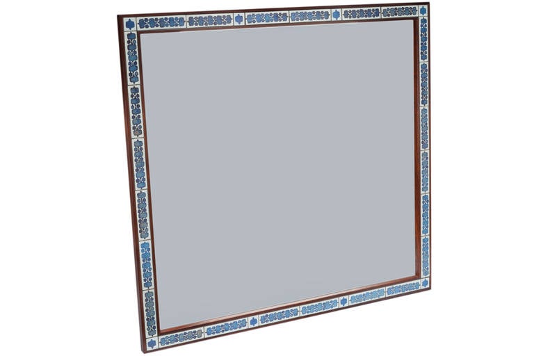 Beautiful Danish rosewood mirror manufacture by Haslev with inset handmade Royal Copenhagen tiles designed by Nils Thorsson. Mirror measures 43 inches square. Signed with Haslev label to back or mirror and tiles signed with RC mark as well.