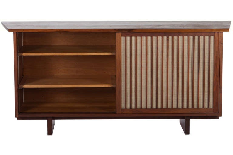 George Nakashima designed American walnut cabinet with sliding doors with  pandanus cloth,2 adjustable shelves, and four drawers. Also with free-eddge top and double sided overhang.Cabinet comes with complete provenance.