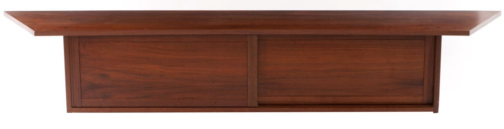 Fine walnut Nakashima wall hanging cabinet with a double overhanging and pegged top. With two sliding doors and interior shelf. Cabinet comes with Provenance and signed with clients name to underside of cabinet (Levy).
