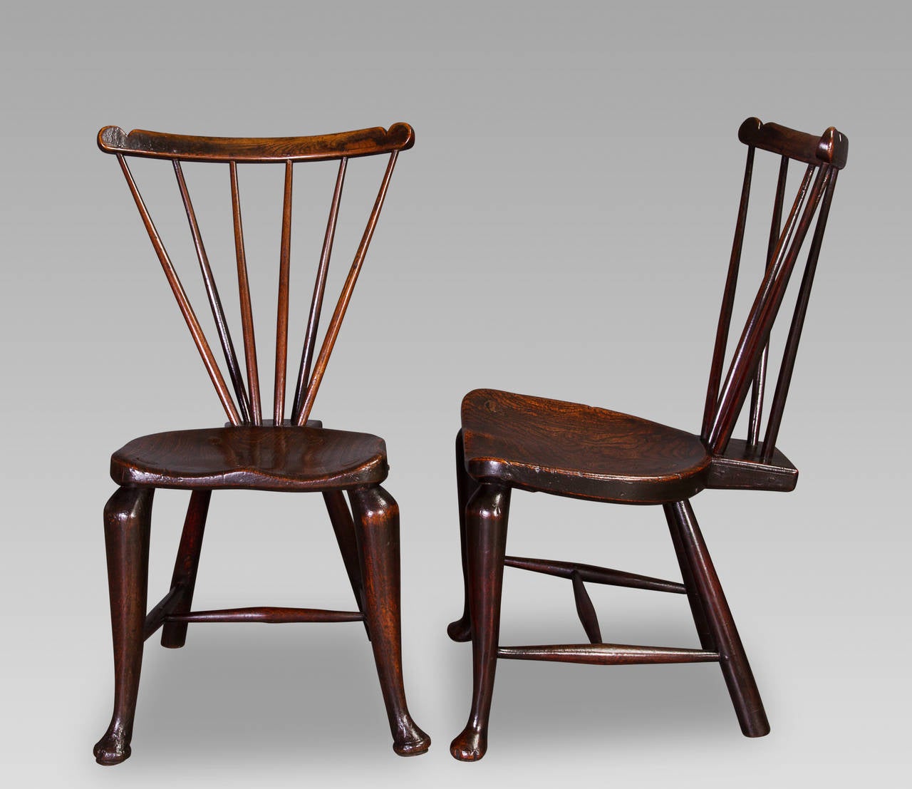 As examples of early Windsor chairs, these stylish pieces are about as good as they get.

Each with a triangular stick-back radiating from an exaggerated rear wedge to the elm deeply dished saddle-seat and held in place by a scroll-ended top