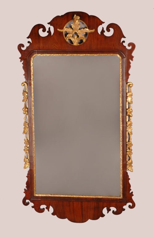 With a pierced cresting containing a shaped gilt leaf decoration to the roundel, the sides flanked by gilt pendant foliate garlands and a shaped apron. Mirror plate replaced.
