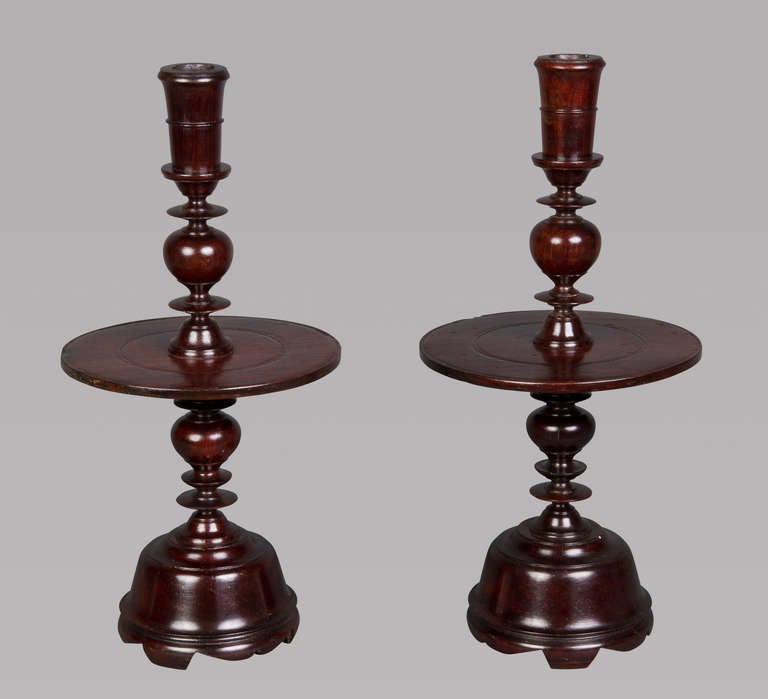 Each having a flared candle holder with a wide mid-filet and multi-knopped and acorn-turned stem with a broad flat central drip pan all raised on a domed and spreading base with scroll-cut footrim. 

Jacaranda is native to Brazil and the tropical