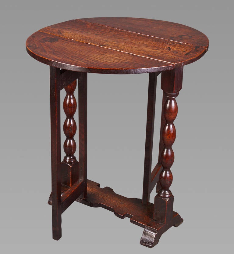 A very good gateleg side table of small proportions with an almost circular top above elongated ball or bobbin-turned supports on a shaped base with sledge feet. This table has a very fine deep color and patina, and is in excellent condition.