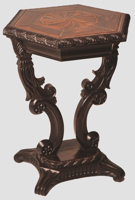 With hexagonal molded top with leaf-carved edge enclosing six calamander-veneered segments banded with chevrons of bone and ebony centered by a rosette of specimen woods including amaranth, satinwood, end-cut palm and other woods above a molded