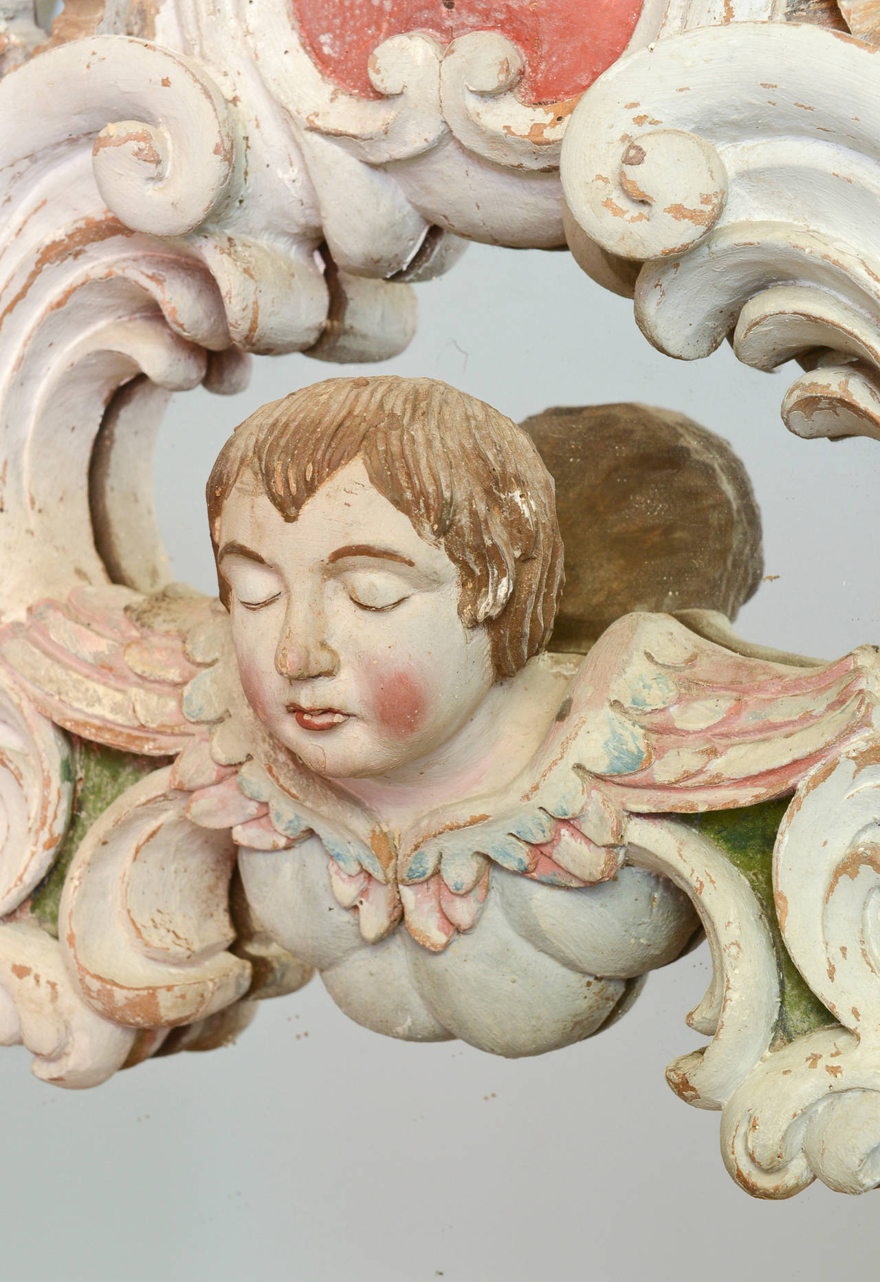 19th century antique hand-carved Venetian mirror. This Italian Rococo style frame is carved in a beautiful shell and floral motif. The centerpiece of the frame is a large carved shell featuring a carved figurehead of an angel. It is painted in