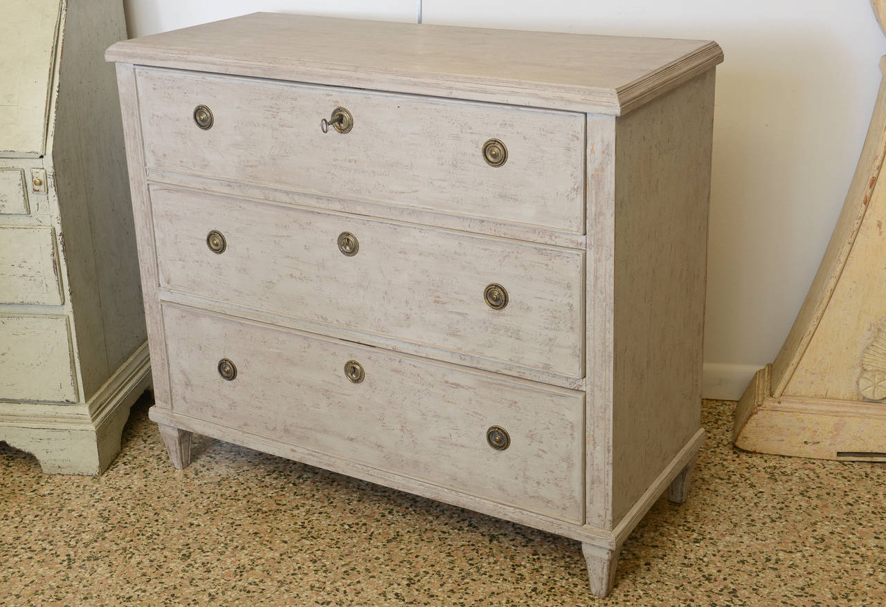 Antique 19th Century Swedish Chest with three drawers that increase in size from top to bottom. Each drawer has original locks and beautiful hardware; cabinet is refreshed distressed paint in a pale Swedish grey colour. The front edges of the chest