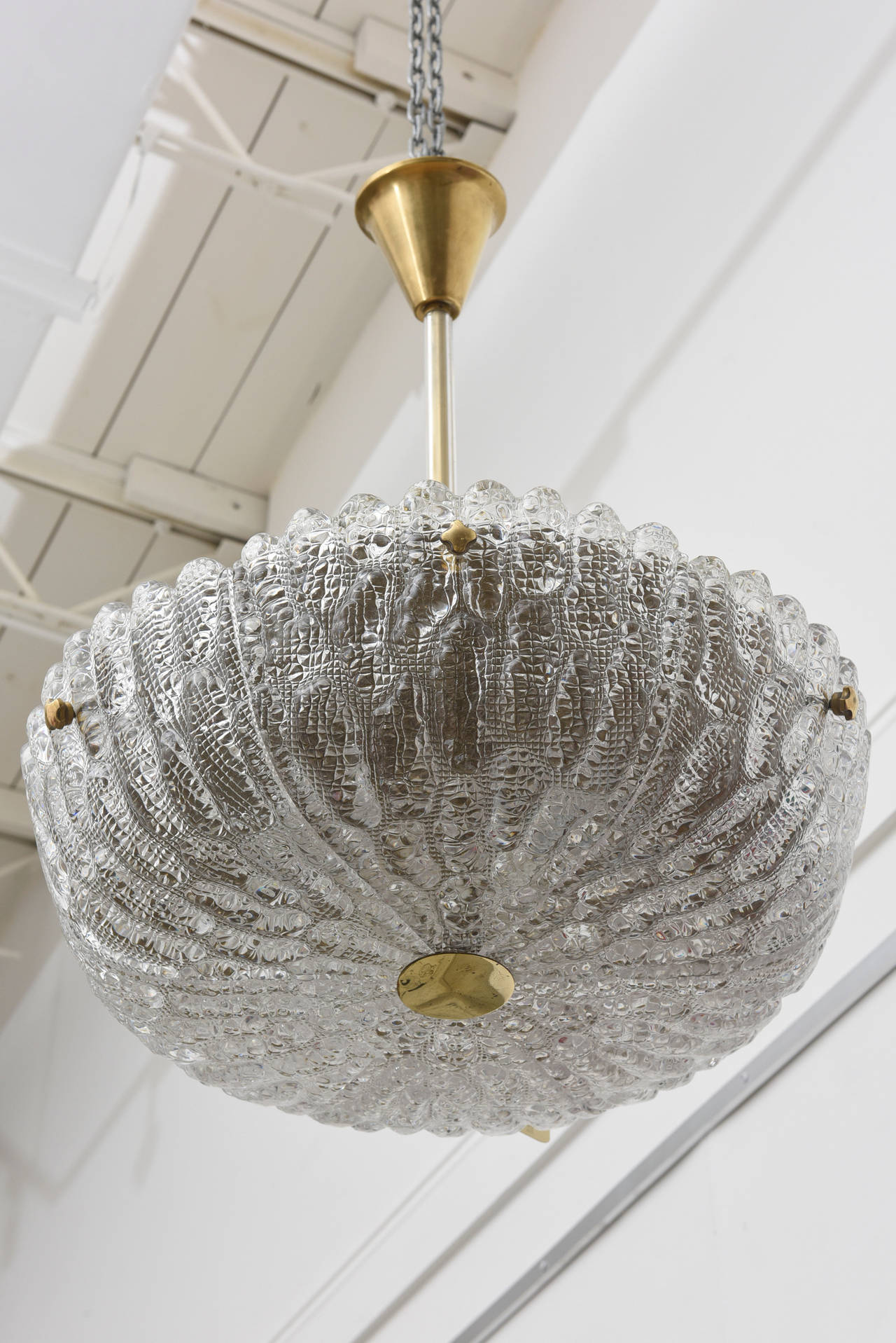 Crystal ceiling lamp by Carl Fagerlund for Orrefors, Sweden. Exquisite bowl shaped, vintage 1960s crystal hanging ceiling lamp with brass fittings in heavily textured ice glass. The brass stem has a glass leave covering. Brass cover over top of