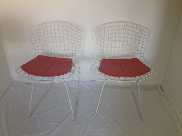 Set four white Harry Bertoia Chairs with knoll original orange seat all original together with a Formica white top stainless steel 4 legged table all original very good condition  