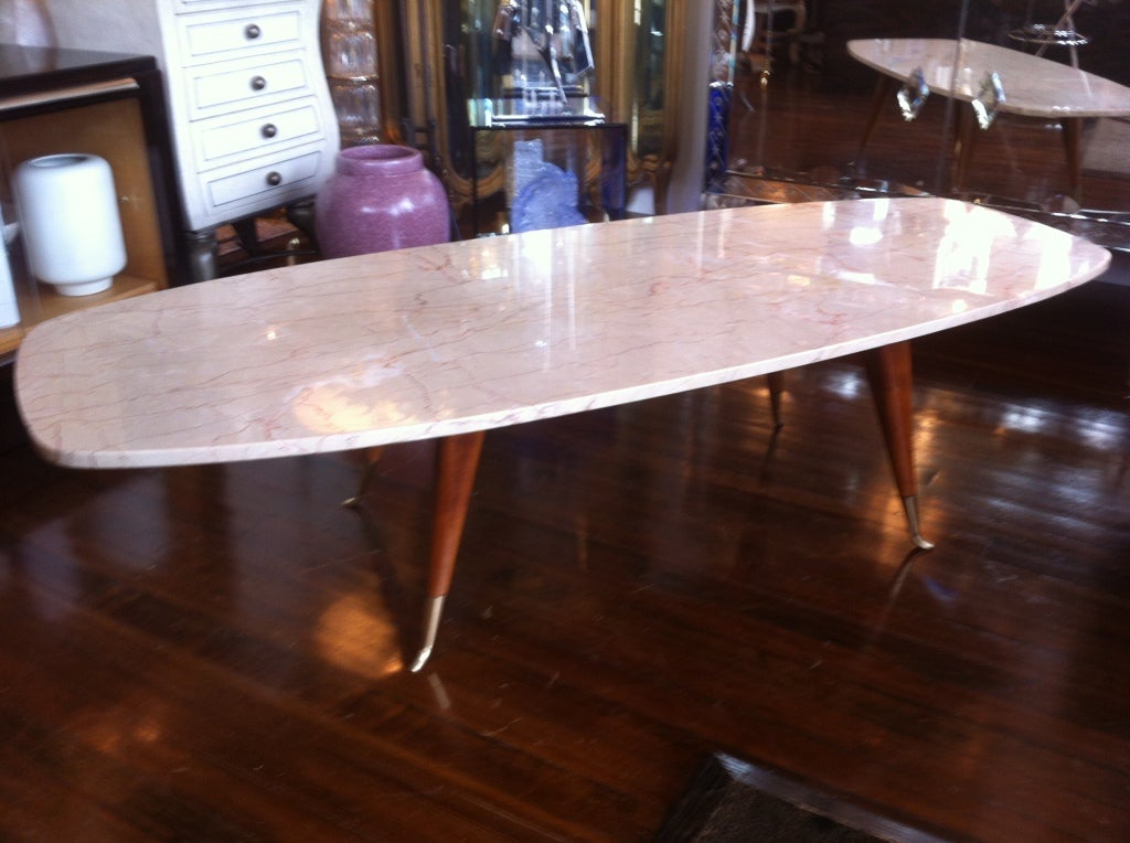 Marble veined, top slim lined leg. bronze tip footed cocktail table