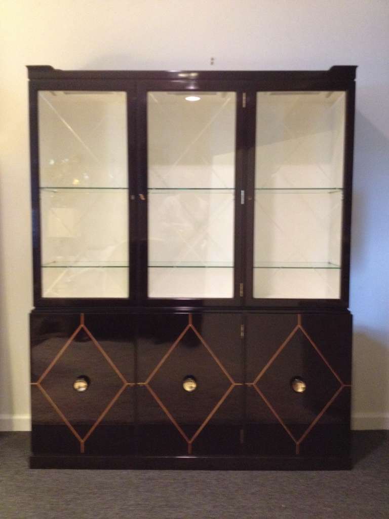 Tommi Parzinger Dark Mahogany and Inlaid Hollywood. In a diamond pattern, glass doors are Diamond beveled with creme interior, six glass shelves in top section, and bottom compartments each side two shelves, center section with draws. In restored
