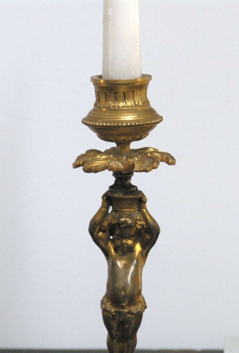 Pair of French figural gilt bronze candelabra on grey marble plinths.
