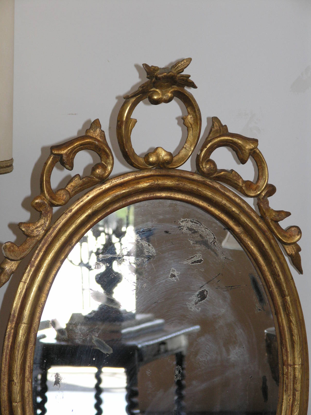 The oval plate within a moulded frame surmounted by a pierced cresting raised on a giltwood serpentine base.