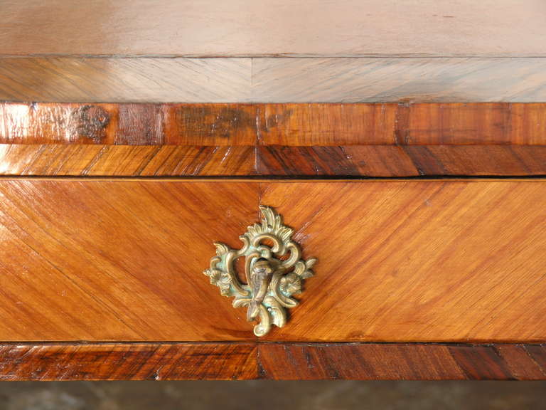 The shaped top inset with a beige tooled leather writing surface above three drawers , raised on cabriole legs ending in scrolled sabots. The reverse side with three dummy drawers