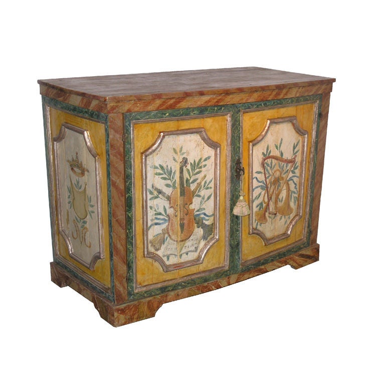 Italian parcel gilt , faux marble and polychrome decorated credenza. Rectangular top with moulded edge above a pair of paneled doors raised on bracket feet.