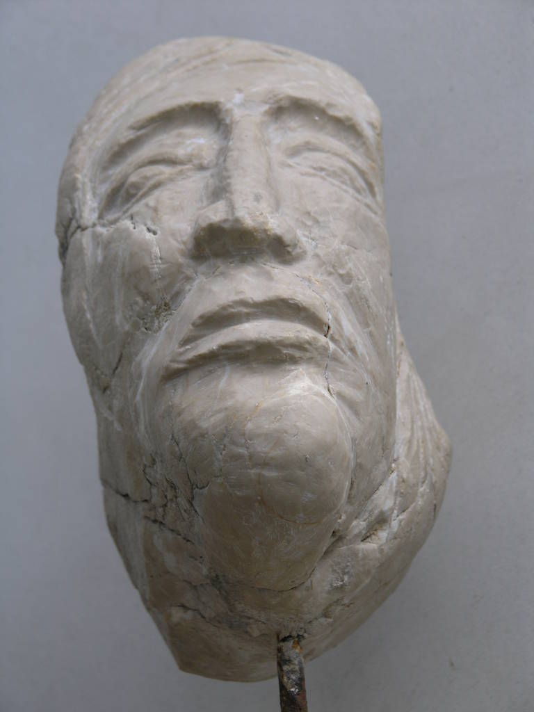 Carved marble head depicting a female head on slab marble base.