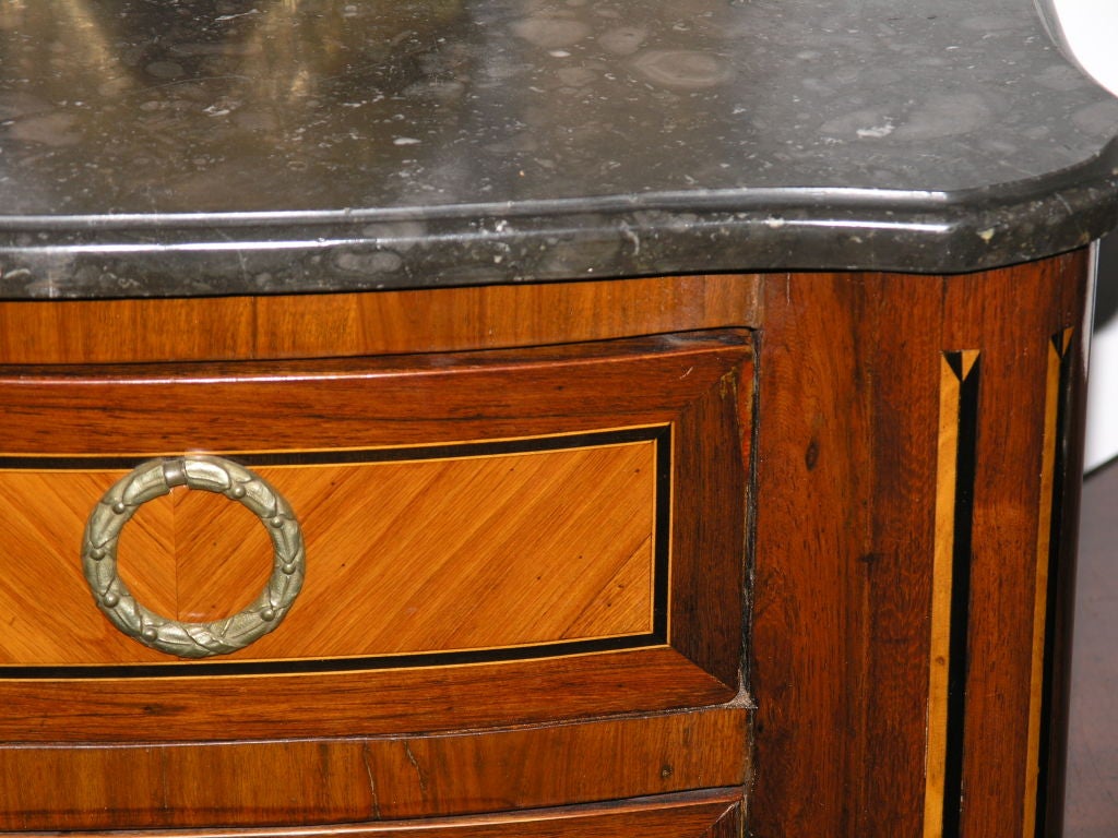 The rectangular white-veined grey marble with outset rounded corners over a conforming case with four drawers, flanked by rounded inlaid continuing to turn the legs with cast feet.