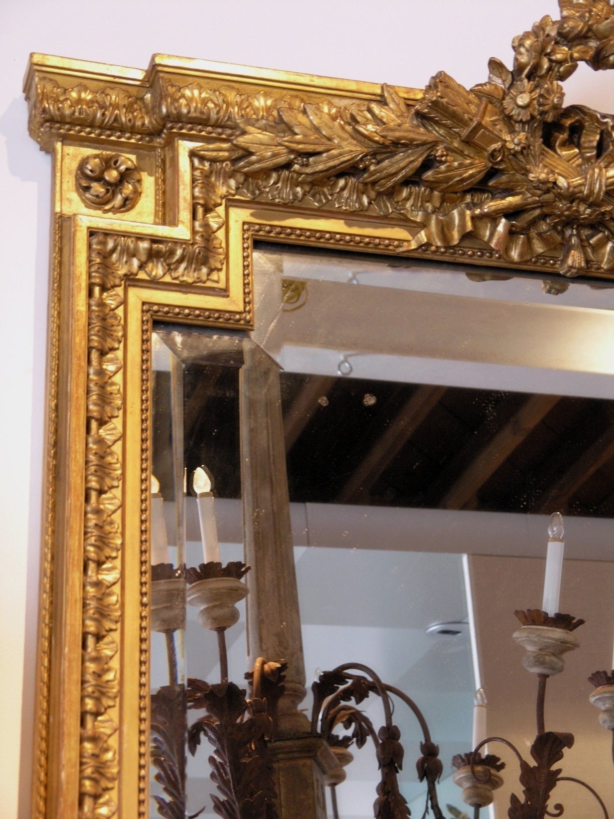 French Empire 24-karat giltwood mirror, the rectangular beveled plate within beaded and stiff leaf borders, surmounted by a cresting of quiver of arrows and flora.