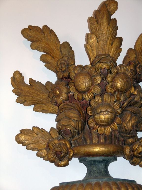 Carved in the form of a vase issuing flowerheads and foliage, raised on a shaped socle 