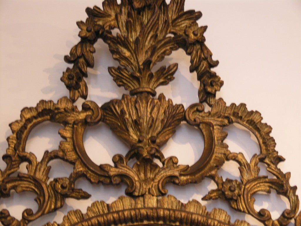 The arched plate within marginal borders and surmounted by a bold pierced foliate C-scroll cresting leading to similar pendants, on C-scroll outswept feet centered by a leafy apron.