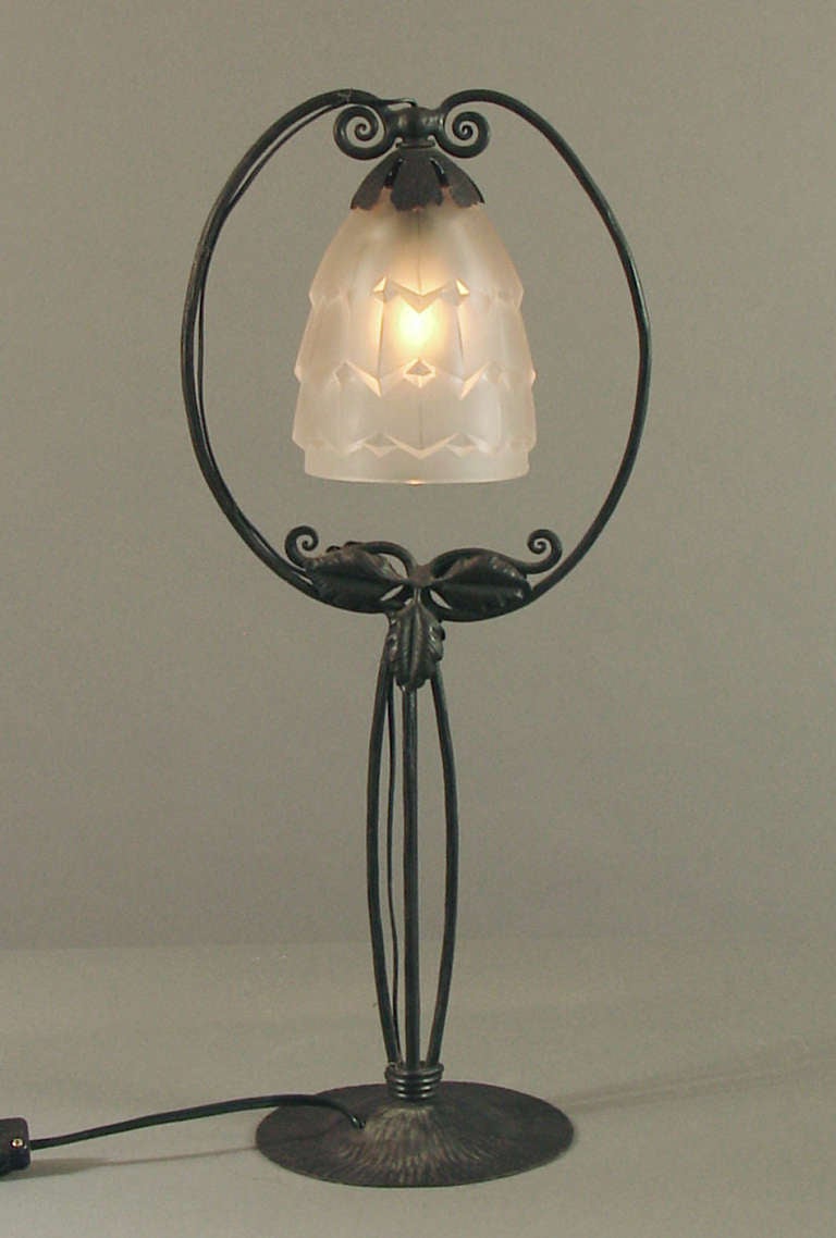 Here's a nicely designed, hand-wrought iron lamp from 1920's France.
Every centimeter -- yea, millimeter -- has been decorated by the ferronnier.  The geometric shade is substantial in the French mode and provides a contrast to the more organic