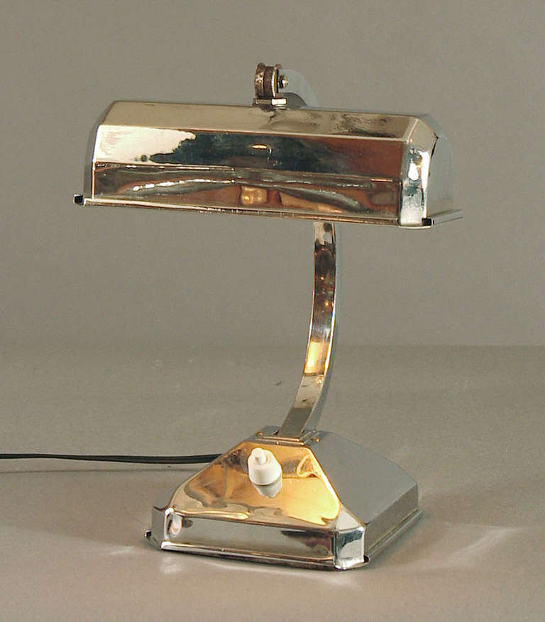 Here's a small, cute French Art Deco table or desk lamp, made of solid brass, chrome-plated (with its original finish), with a heavy iron weight in the bottom for stability.  You can move the arm forward or backward as the photos indicate, and the