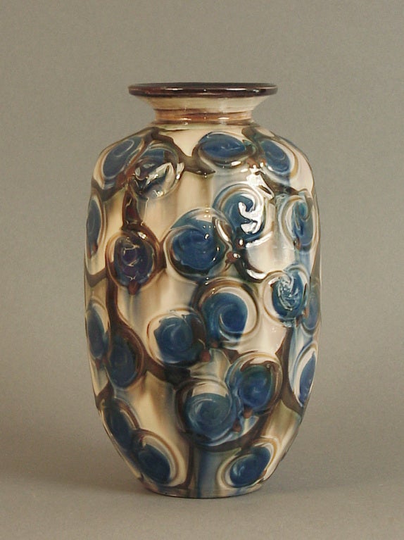 This striking vase by Kahler is incised and decorated with nubs of brown along with the swirls of blue and brown 