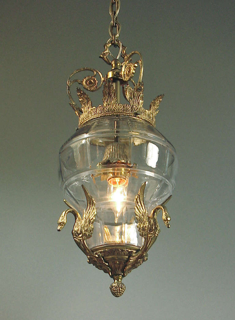 Judging from the swirling, organically fashioned design details of the canopy, I'd say this light hails from the first 20 years of the last century.  It's made of solid brass and has vestiges of the original gilt finish.  The glass fixture is
