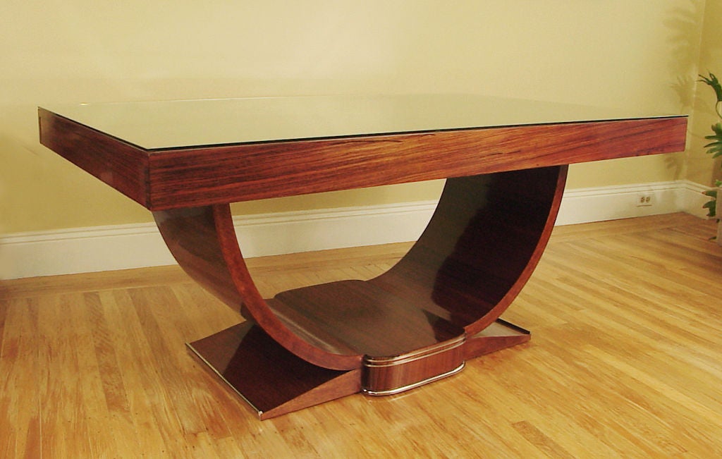 This French Art Deco Rosewood dining table is in superb antique condition, with a French polished finish and a cut-to-order protective glass top.  It seats six comfortably, measuring about 63 inches long and 39 wide.  Nickel-plated  embellishments