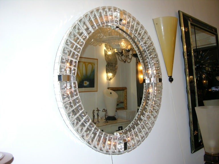 Round Venetian mirror from 1960s on a wooden and iron structure, superbly hand crafted; the deep recessed round frame whole covered in mirror is nearly 4 inches deep; the raised front frame has a fabulous design with 4 cardinal bridges covered in